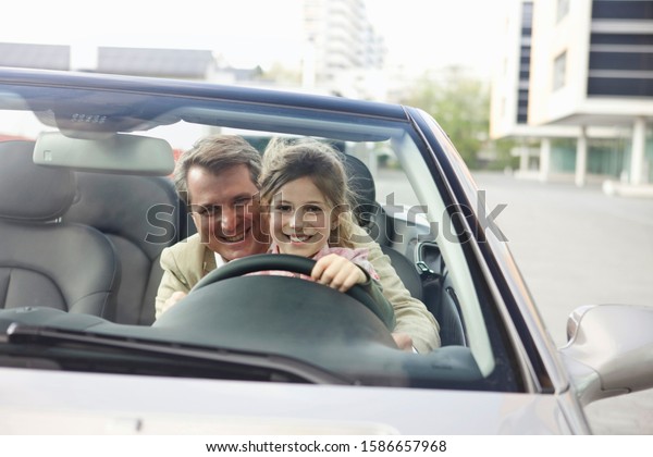Father\
teaching daughter to drive car, Munich,\
Germany
