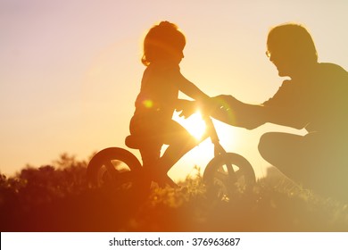 Father Teaching Daughter To Ride Bike At Sunset