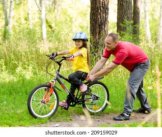 Father Teaching His Daughter To Ride A Bike