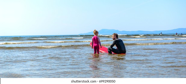 A father teaching his kids to surf in a lesson on the beach.  