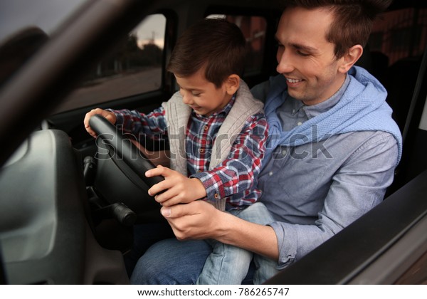 Father teaching\
his little son to drive a\
car