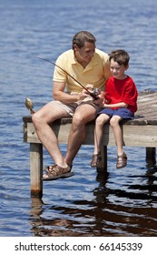 A Father Teaching His Son Fishing And Catching A Fish On A Jetty Outside In Summer Sunshine