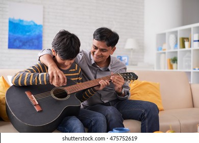 Father Teaching His Son How To Play Guitar