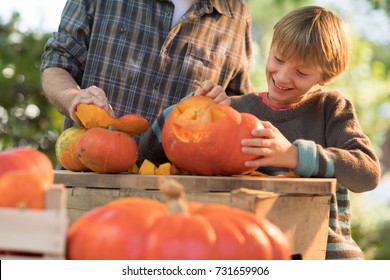 a father teaching his son how to carve a pumpkin for halloween.