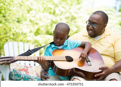 Father Teaching  His Son To Play Guitar