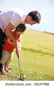 Father Teaching His Son To Play Golf