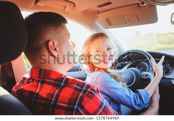 father teaching kid daughter to drive a car,\
family traveling on summer\
vacation