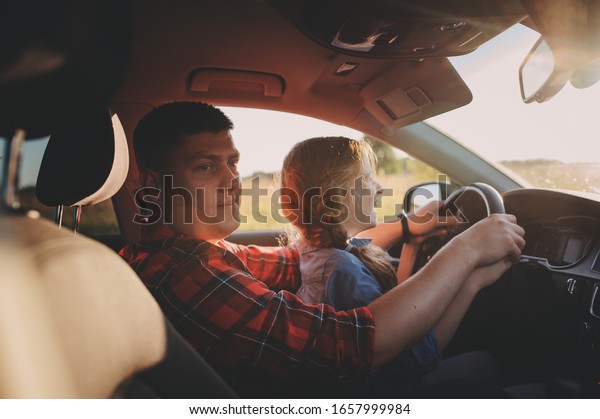 father teaching kid daughter to drive a car,\
family traveling on summer\
vacation