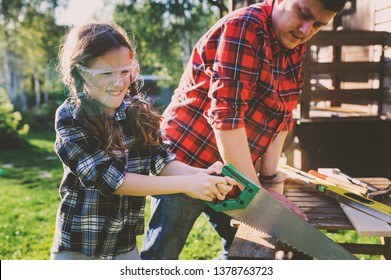 father teaching kid daughter to use tools. Girl helping dad with building work outdoor in summer, country house on background - Powered by Shutterstock