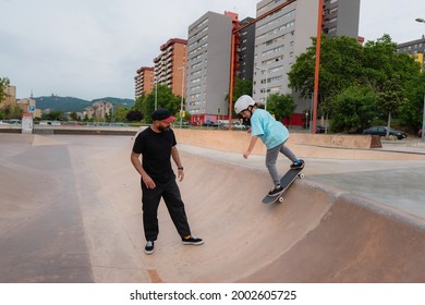 Father teaching skateboarding to his young daughter at a skate park - Powered by Shutterstock