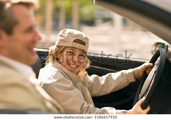 Father\
teaching son to drive car, Munich,\
Germany