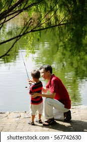 Father Teaching Son To Hold Fishing Pole