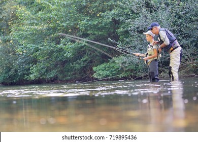 Father teaching son how to fly-fish in river