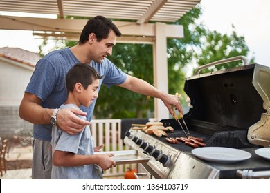 father teaching son how to grill hot dogs and bonding