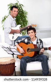 Father Teaching Son How To Play The Guitar