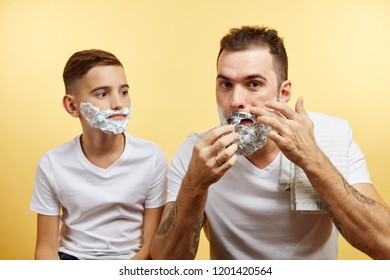 Father Teaching Son How To Shave On Yellow Background