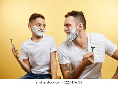 Father Teaching Son How To Shave On Yellow Background