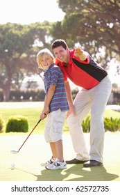 Father Teaching Son To Play Golf On Putting On Green