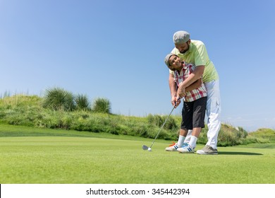 Father teaching son playing golf at club