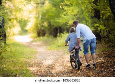 Father Teaching Son To Ride Bike In Countryside