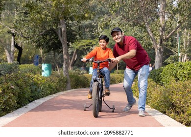 Father teaching son riding bicycle at park
