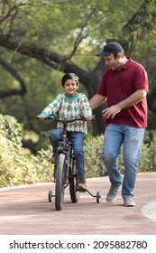 Father Teaching Son Riding Bicycle At Park
