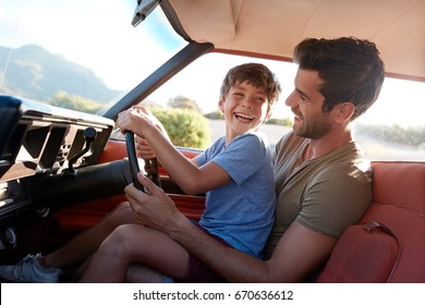 Father Teaching Young Son To Drive Car On Road Trip