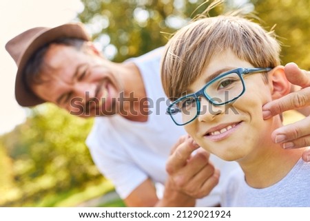 Father teases his son with glasses on a summer vacation trip in the park