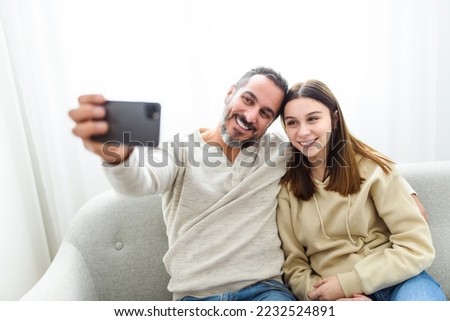 A father with teen child daughter having fun using cellphone at home