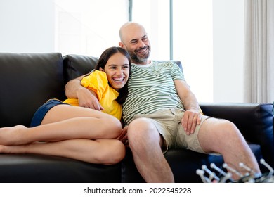 Father And Teenage Daughter Laughing At Funny Movie Or Tv Show Sitting In The Sofa At Home