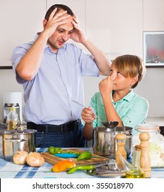 Father And Teenage Son Cooking A Dinner And Smiling 