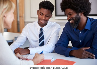 Father And Teenage Son Having Discussion With Female Teacher At High School Parents Evening