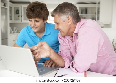 Father and teenage son using laptop