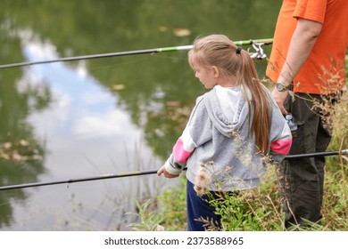 Father and teenager daughter fishing on the lake, river. They hold fishing rods in hands. Summer time, nature, relationships - Powered by Shutterstock