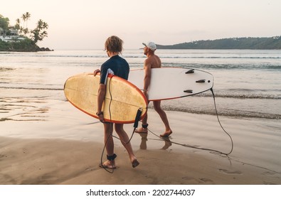 Father with teenager son with surfboards walking by sandy ocean beach on Sri Lanka island. They have a winter vacation and enjoying a beautiful sunset light. Family active vacation concept - Powered by Shutterstock