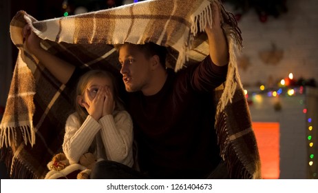 Father Telling Horror Christmas Story For Little Girl Sitting Under Cozy Plaid