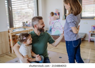 Father three little daughters getting drawings from them at home 