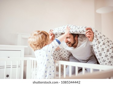 Father With A Toddler Boy Having Fun In Bedroom At Home At Bedtime.