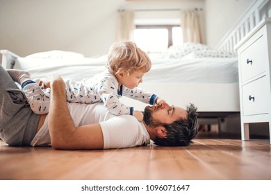 Father With A Toddler Boy Having Fun In Bedroom At Home At Bedtime.