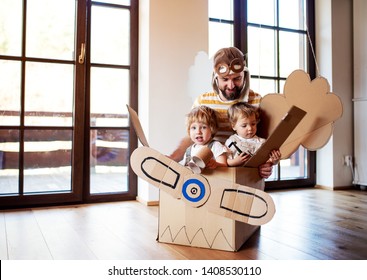 A father and toddler chidlren playing with carton plane indoors at home.
