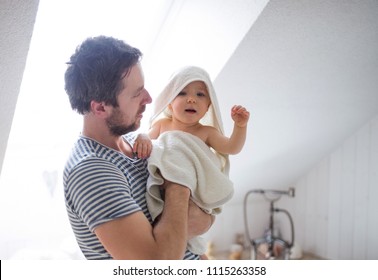 Father With A Toddler Child Wrapped In Towel In A Bathroom At Home.