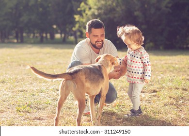 Father And Toddler Feeding And Walking With Dog