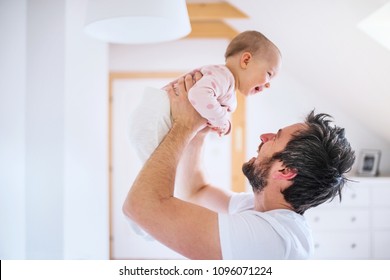 Father with a toddler girl in bedroom at home, having fun.