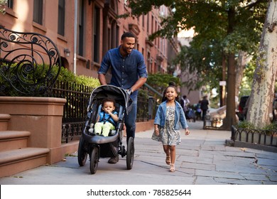 Father and two daughters taking a walk down the street