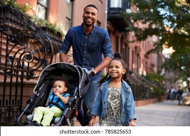 Father and two daughters taking a walk down the street, close up