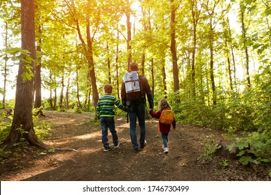 father and two kids with backpack hiking in forest. Social Distancing. Digital detox. Staycations, hyper-local travel,  family outing, getaway, natural environment