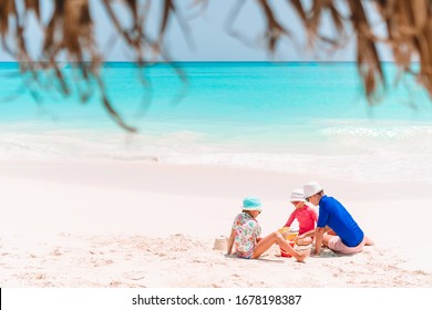 Father And Two Kids Playing With Sand On Tropical Beach. Family Vacation