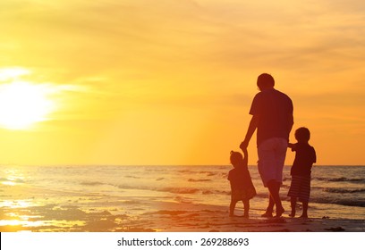 Father And Two Kids Walking On Beach At Sunset