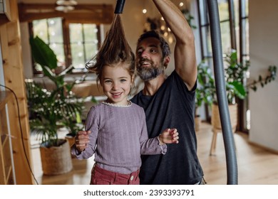 Father vacuuming girl's hair with vacuum cleaner. Father and daughter cleaning the house, helping with house chores. - Powered by Shutterstock