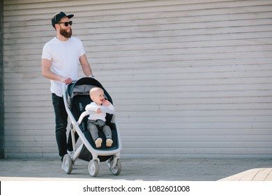 Father walking with a stroller and a baby in the city streets